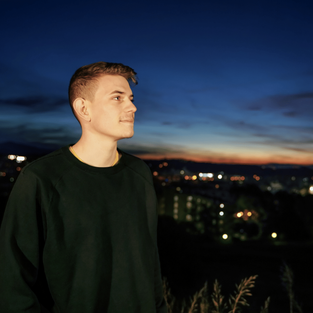 young man looking out at a cityscape at night
